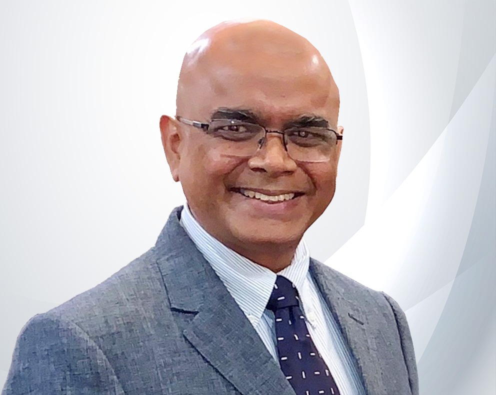 Dr. David Singh, Chairman of the Board of Governors of St. Stanislaus College, smiling in a grey blazer and navy tie